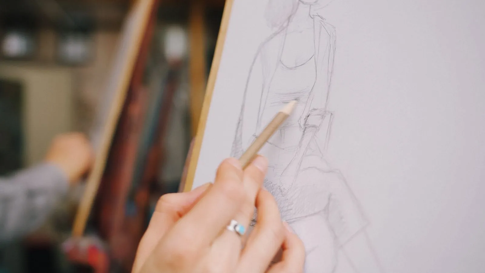 Hand drawing a sketch of a person on a canvas in an artistic studio setting.